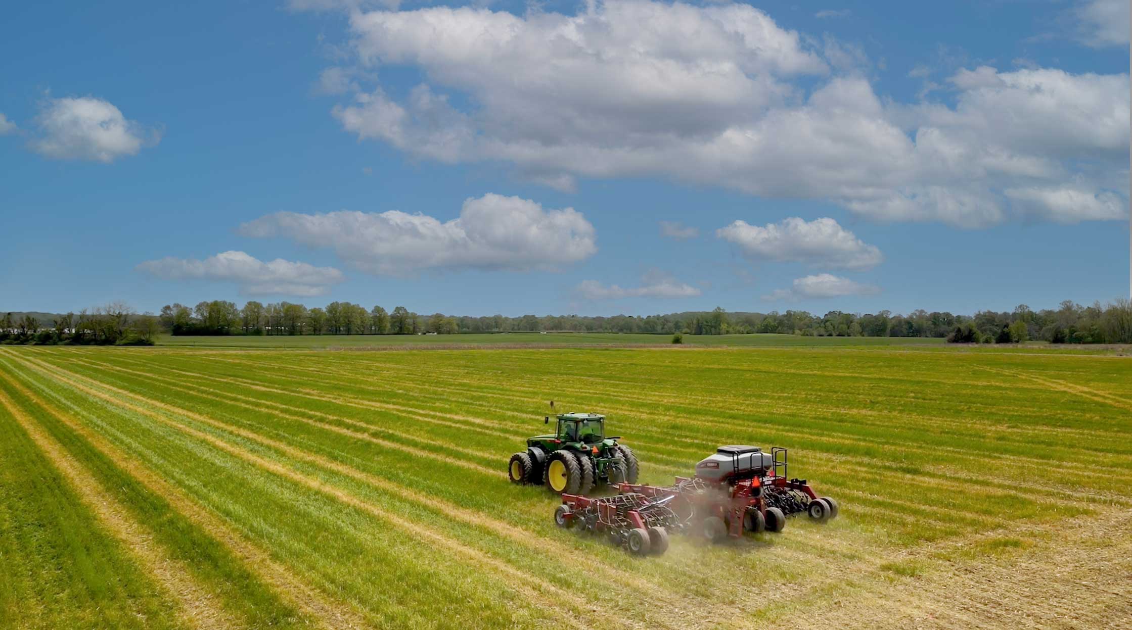 A tractor driving across a green field.