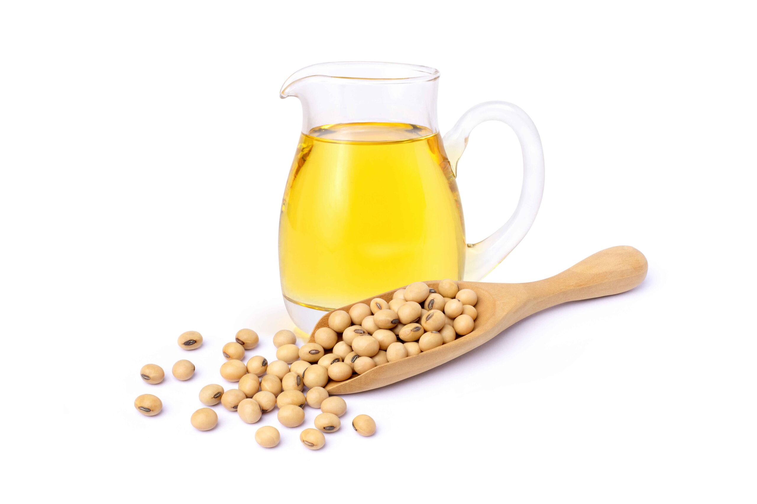 Glass pitcher of oil behind wooden scoop of Milo seeds on white background.